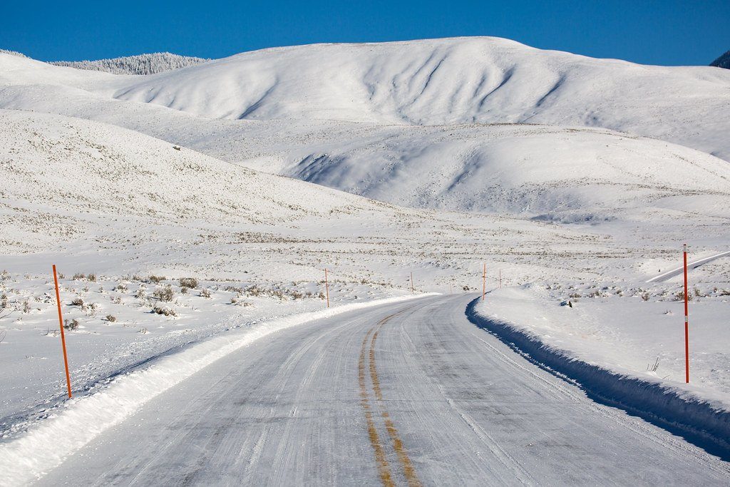 A snowy road winding through white hills