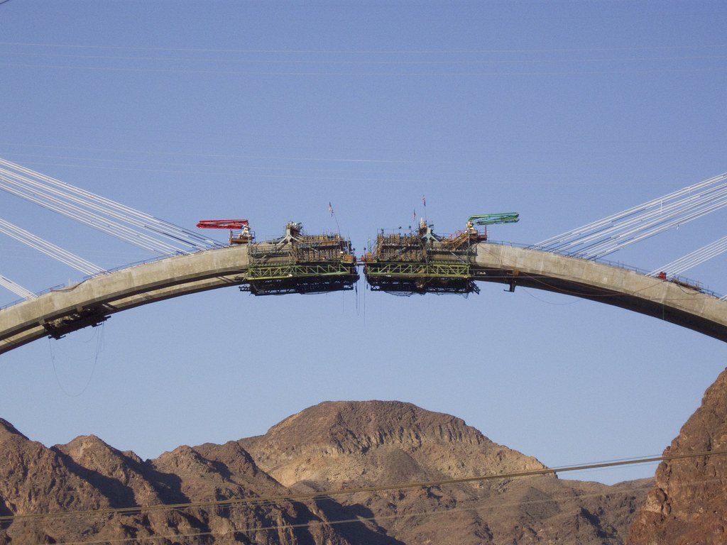 Two halves of an arch bridge about to be joined over a canyon