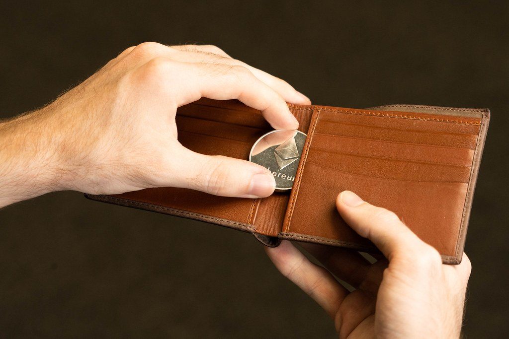 Hands taking a coin out of a leather wallet