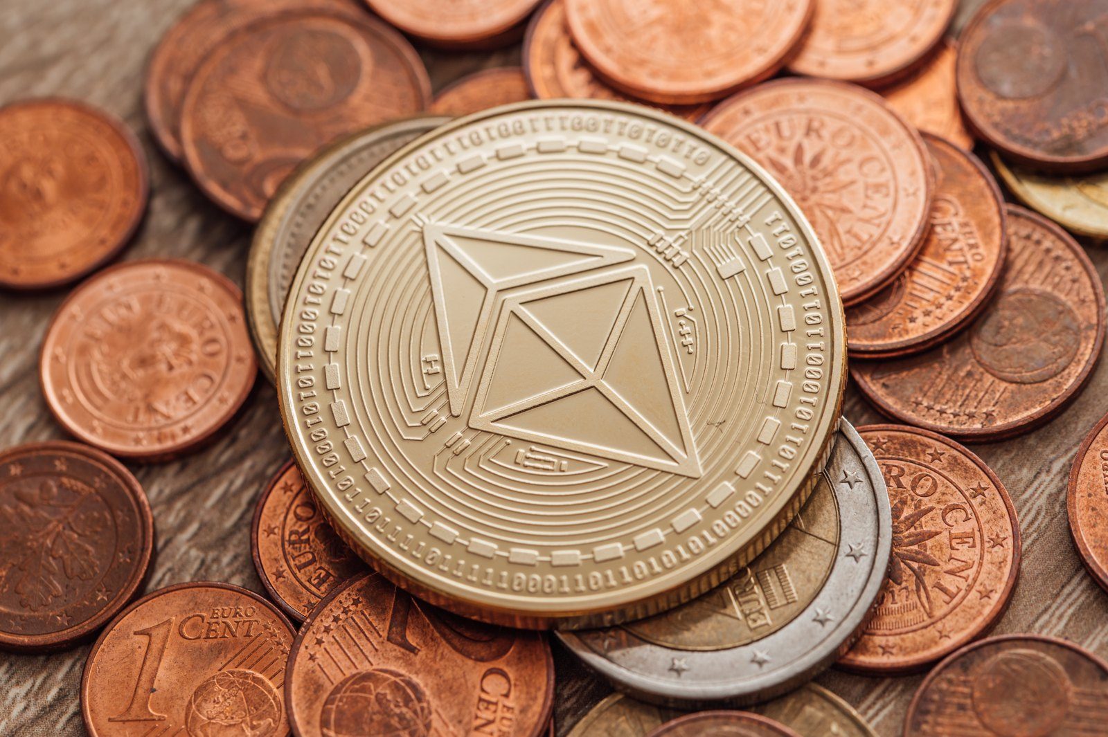A gold-coloured crypto coin resting on copper coins