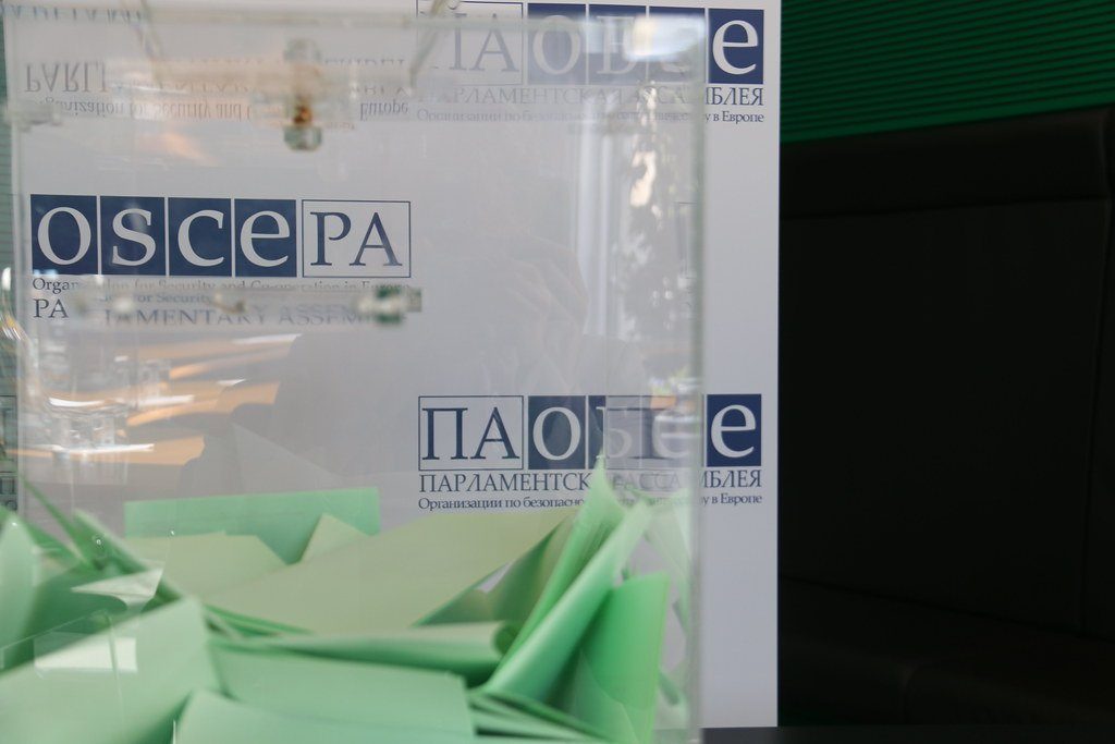 A transparent ballot box filled with voting slips